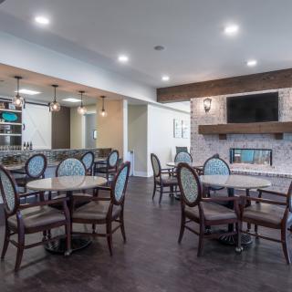 A modern dining area featuring several tables and chairs, a fireplace, and a wall-mounted television.