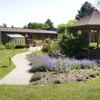 A peaceful garden with a gazebo and colorful flower beds along a walking path.