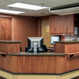 A reception desk area in an office setting with wooden cabinetry and computer monitors.