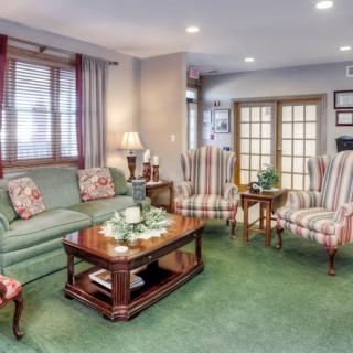 A cozy living room featuring a green sofa, striped armchairs, and a wooden coffee table.