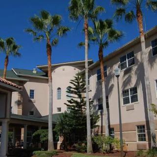 A modern building surrounded by palm trees under a clear blue sky.