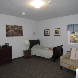 A cozy bedroom with a single bed, dresser, and framed wall art.