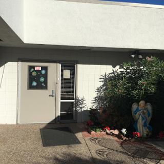 An entrance to a building, featuring an angel statue and a garden.