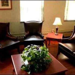A cozy seating area featuring leather chairs and a wooden table with a decorative plant, illuminated by a table lamp.