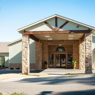 A sunny view of a building's entrance featuring stone and wood accents.
