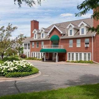 A charming brick hotel with a landscaped driveway and lush greenery.