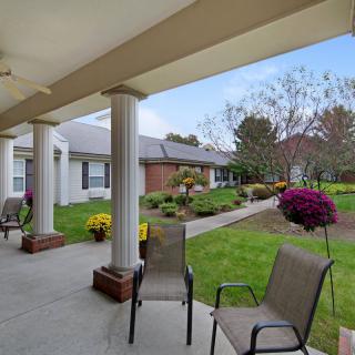 A covered patio with chairs overlooking a landscaped garden.