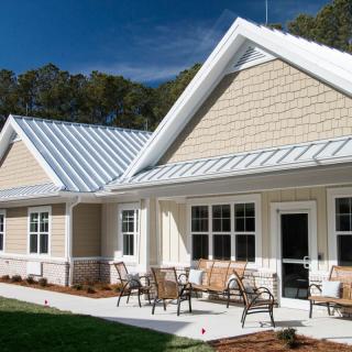 A modern house with a metal roof and outdoor seating area on a sunny day.