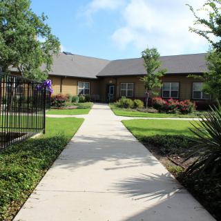 A well-maintained garden with a concrete pathway leading to a residential building.