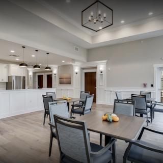 A modern dining area with tables and chairs, adjacent to a kitchen space.