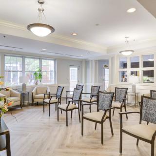 A modern, bright meeting room with arranged chairs and large windows.