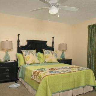 A cozy bedroom with a neatly made bed, featuring floral bedding and matching lamps on dark wooden nightstands.