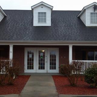 A brick house with a porch and multiple windows.