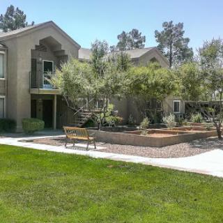 A peaceful residential complex featuring lush greenery and a welcoming bench.