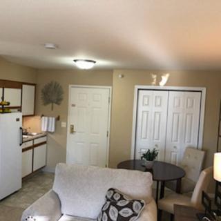 A cozy apartment interior featuring a small living area with a kitchenette and seating.