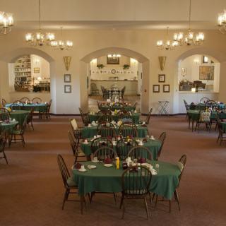 A spacious dining area with neatly arranged tables and elegant chandeliers.