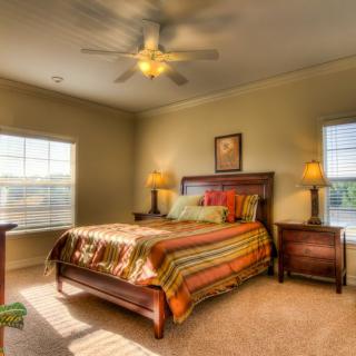 A cozy bedroom with warm lighting and a ceiling fan.