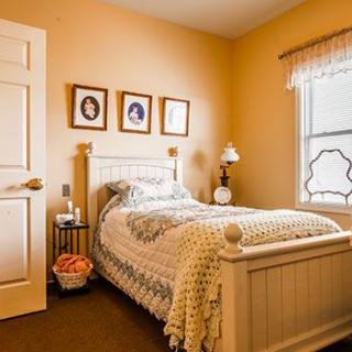 A cozy bedroom featuring a single bed with vintage decor and warm lighting.