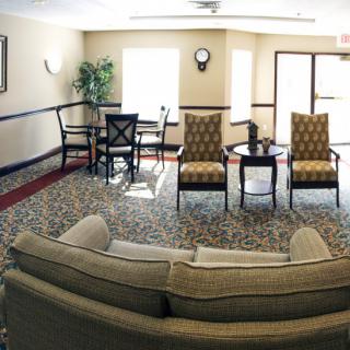 A cozy living room with a sofa, chairs, and a small table arranged on a patterned carpet.