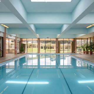 A serene indoor swimming pool, featuring large windows and bright blue walls that create a tranquil atmosphere.