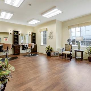 A modern hair salon with wooden flooring, styling stations, and decorative plants.