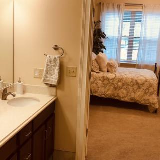 View of a cozy bedroom through a bathroom entrance.