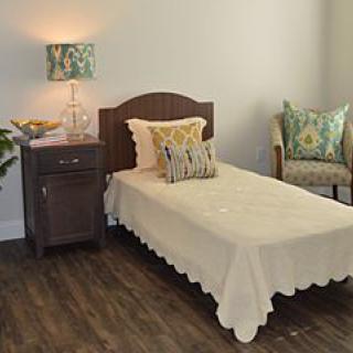 A cozy bedroom with a single bed, nightstand, and decorative pillows.