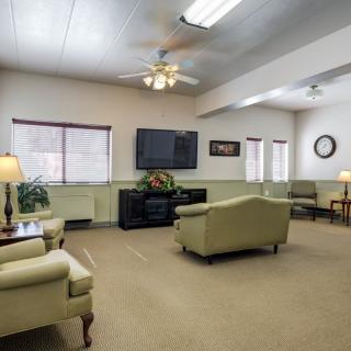 A cozy living room with sofas, a television, and multiple windows bringing in natural light.