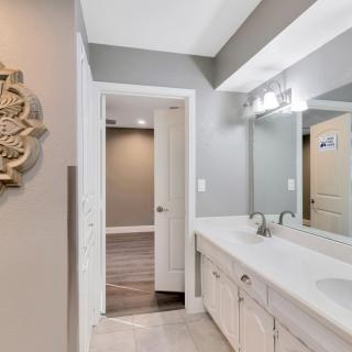 A modern bathroom with a large mirror and dual sink setup, featuring sleek lighting and decorative wall art.