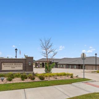 A school building with a sign and well-maintained landscaping under a clear blue sky.