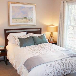 A cozy bedroom with a well-made bed, decorative pillows, and a bedside lamp.