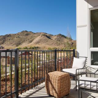 A scenic balcony with outdoor furniture overlooking mountains under a clear blue sky.