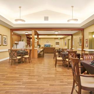 A spacious dining area with neatly arranged tables and chairs, featuring a hardwood floor and modern lighting.