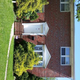 A brick house with a well-kept front yard and greenery.