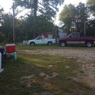 A view of a gravel driveway featuring two parked vehicles in a rural setting.