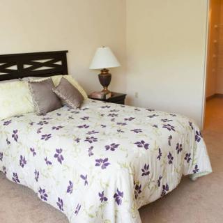 A cozy bedroom with a floral quilt and decorative pillows on the bed.