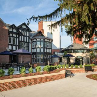 A Tudor-style building with outdoor seating and a garden area on a sunny day.