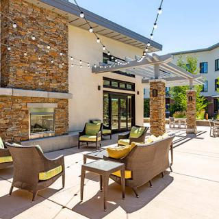 A cozy outdoor patio area with comfortable seating and string lights on a sunny day.