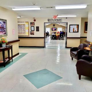 A well-lit hallway leading to a communal area, featuring comfortable seating and decorative art on the walls.