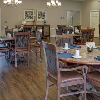 A spacious dining area with multiple tables and chairs on a wooden floor.