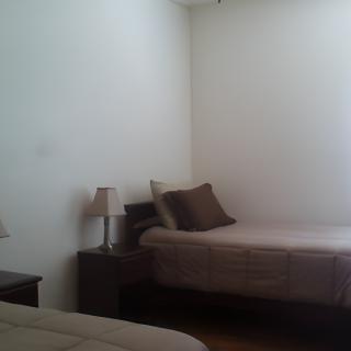 A minimalist bedroom with two beds, side tables, and lamps.