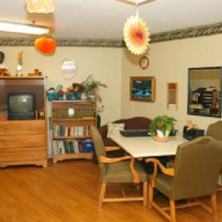 A cozy living area featuring a TV, bookshelf, and a dining table with chairs.