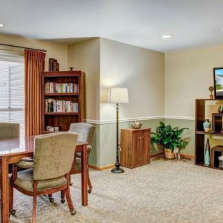 A cozy living room with a table, chairs, bookshelf, and a television.