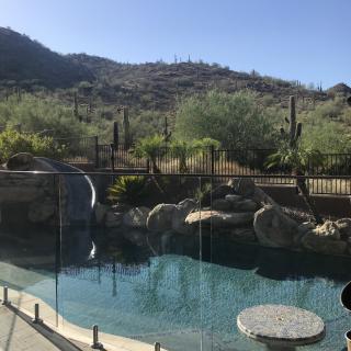 A serene backyard pool set against a desert landscape with mountains and cacti.