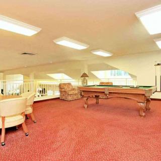 A spacious game room featuring a pool table and comfortable seating on a carpeted floor.