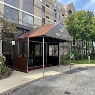 The entrance to a hotel with an awning over the sidewalk.