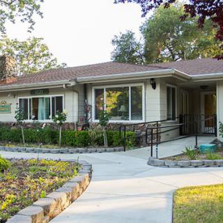 A single-story residential house with a paved walkway and landscaped garden.