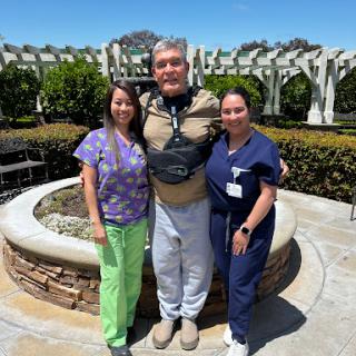 A moment of joy and support in the garden, capturing caregivers and their patient.