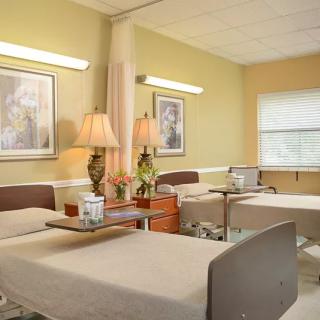 A well-lit hospital room with patient beds and amenities.