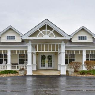 A front view of a large residential building with white columns and a triangular roof design.